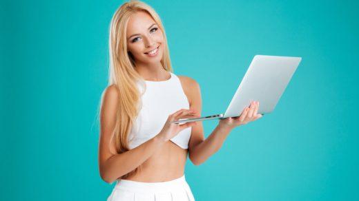 freedidi portrait of a smiling blonde woman using laptop computer and looking at camera isolate SBI 302774878